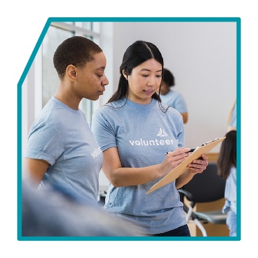 2 volunteer workers looking at a clipboard.