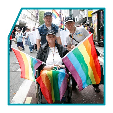 3 people holding rainbow LGBTIQA+ flags.