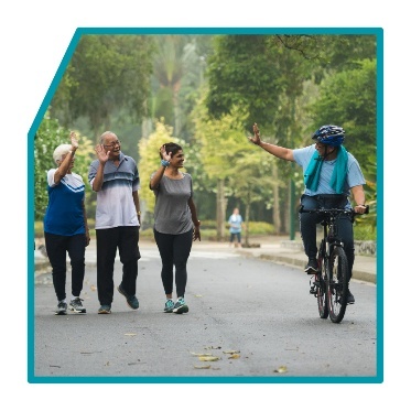 3 people waving at a bike rider.