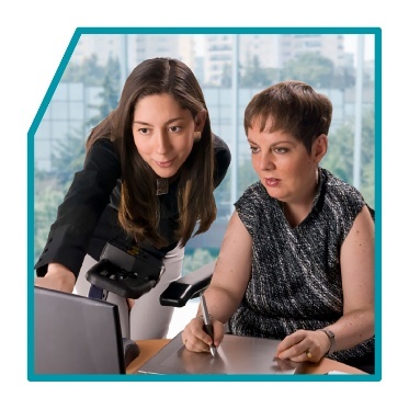 2 people working together and looking at a laptop.